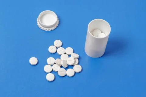 White tablets and bottle for tablets on blue background Stock Photos