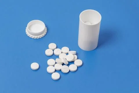 White tablets and bottle for tablets on blue background Stock Photos