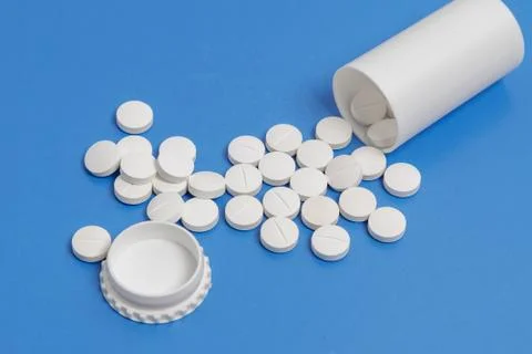 White tablets and bottle for tablets on blue background Stock Photos