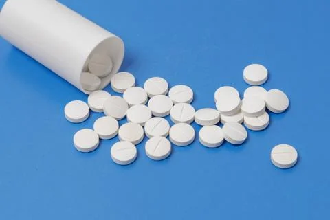 White tablets and bottle for tablets on blue background Stock Photos