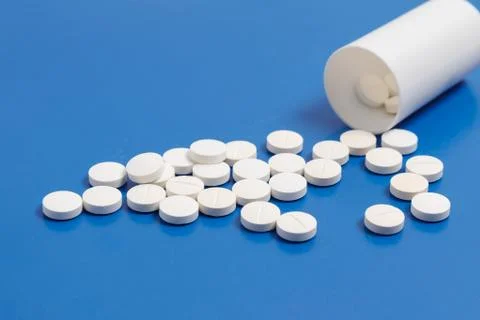 White tablets and bottle for tablets on blue background Stock Photos