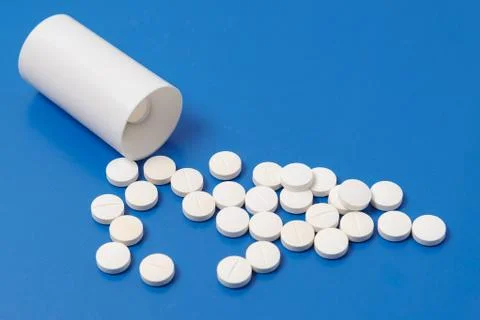 White tablets and bottle for tablets on blue background Stock Photos