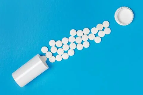 White tablets and bottle for tablets on blue background Stock Photos