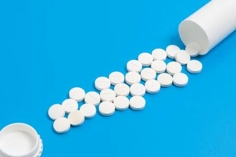 White tablets and bottle for tablets on blue background Stock Photos