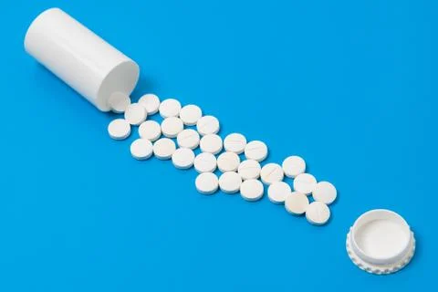 White tablets and bottle for tablets on blue background Stock Photos