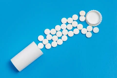 White tablets and bottle for tablets on blue background Foto stock