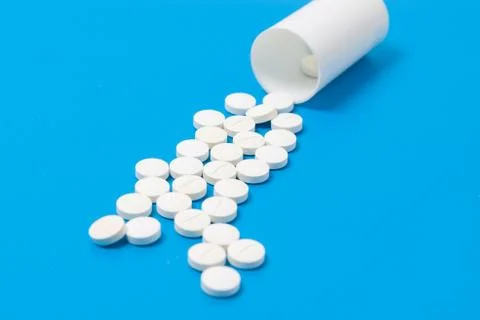 White tablets and bottle for tablets on blue background Stock Photos