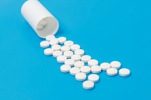 White tablets and bottle for tablets on blue background Stock Photos