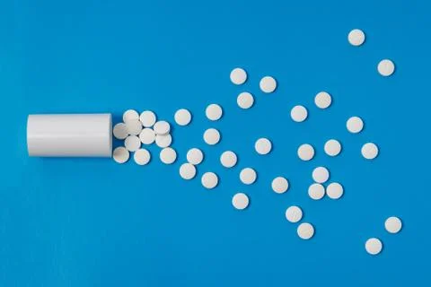 White tablets and bottle for tablets on blue background Stock Photos