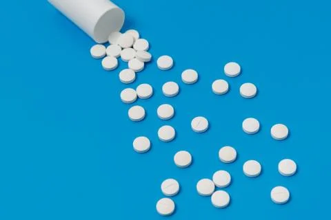 White tablets and bottle for tablets on blue background Stock Photos