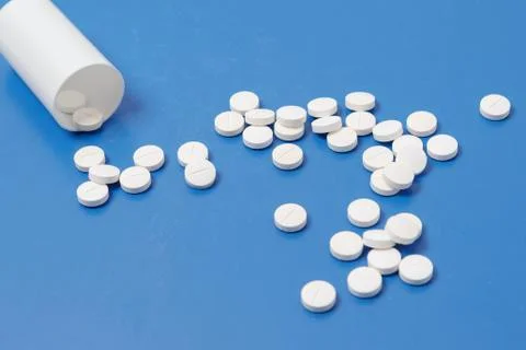 White tablets and bottle for tablets on blue background Stock Photos