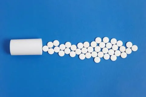White tablets and bottle for tablets on blue background Stock Photos