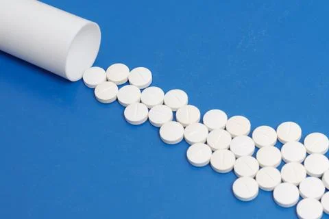 White tablets and bottle for tablets on blue background Stock Photos