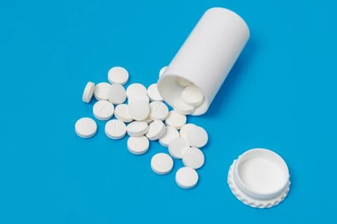 White tablets and bottle for tablets on blue background Stock Photos
