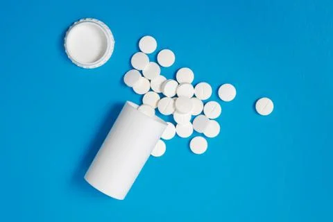 White tablets and bottle for tablets on blue background Stock Photos