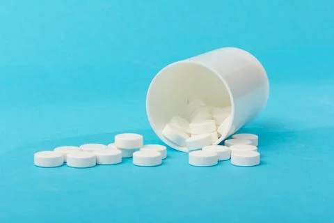 White tablets and bottle for tablets on blue background Stock Photos