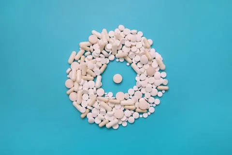 White tablets and capsules in the shape of a circle on a turquoise background Stock Photos