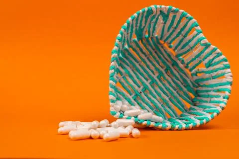 White tablets in a basket on an orange background Stock Photos