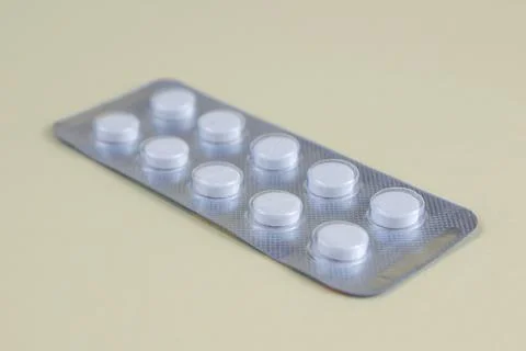 White Tablets in Blister Pack on Light Yellow Background Healthcare and Med.. Stock Photos
