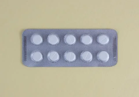 White Tablets in Blister Pack on Light Yellow Background Healthcare and Med.. Stock Photos