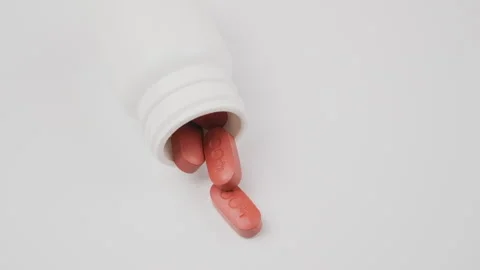 White tablets fall out of the bottle onto the table, slow motion. Antiviral drug Stock Footage 277352396