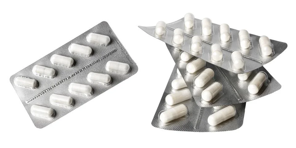 White tablets in a foil shell covered with a plastic shell on a white backgro Stock Photos