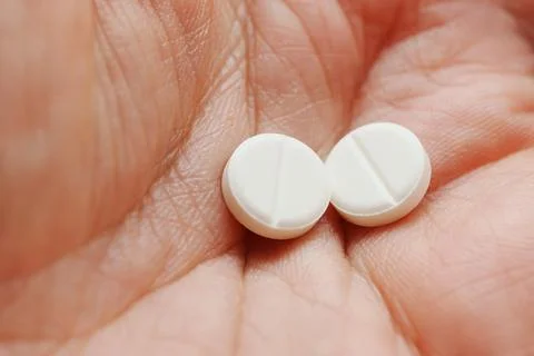 White tablets held in a hand close to the camera for clear view Foto stock