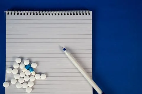 White tablets with notebook and pen on blue surface. Ideal for telemedicine Stock Photos
