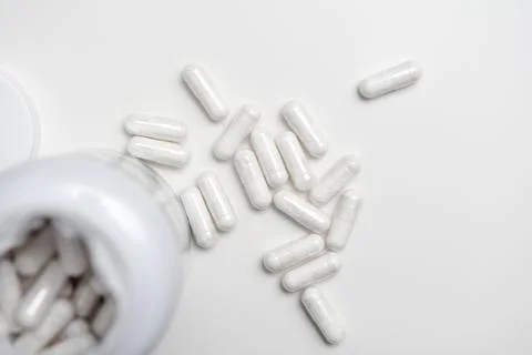 White tablets with an open bottle, some tablets are on the table Stock Photos