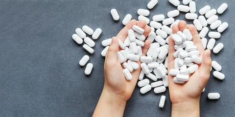 White tablets or pills on the table and hands. Medicine and pharmacy Stock Photos