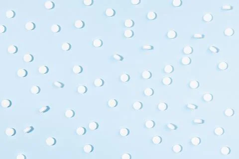 White tablets pattern in hard light on soft light blue color, top view. Medic Stock Photos