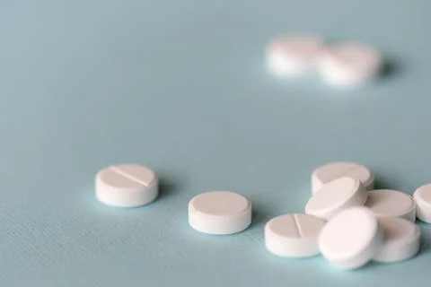 White tablets scattered on a blue background close up Stock Photos