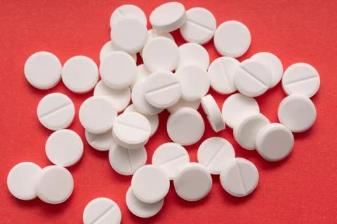 White tablets scattered on a red background Foto stock