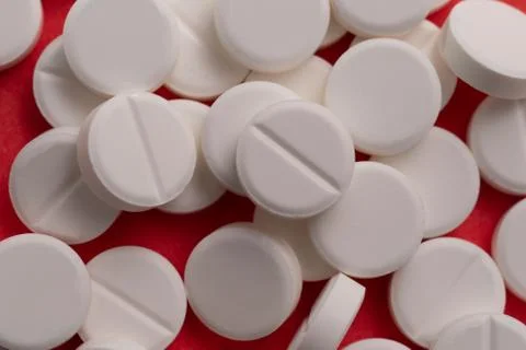 White tablets scattered on a red background 写真素材