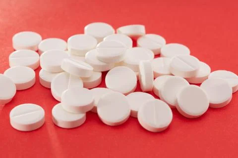White tablets scattered on a red background Foto stock