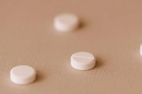 White tablets scattered on a surface close up. Brown color toned Stock Photos