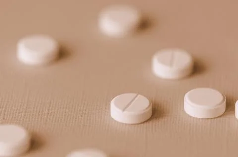 White tablets scattered on a surface close up. Brown color toned 스톡 사진