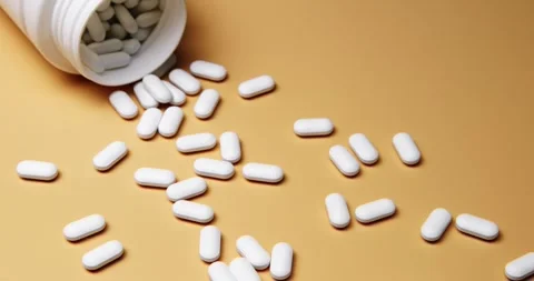 White tablets spilling out of open bottle on to surface Stock Footage 303056652