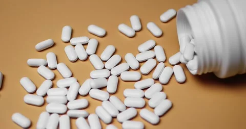 White tablets spilling out of open bottle on to surface 库存影片 303056869