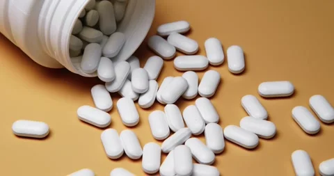 White tablets spilling out of open bottle on to surface Stock-Footage 303056883