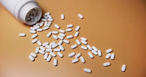White tablets spilling out of open bottle on to surface 스톡 동영상 303056988