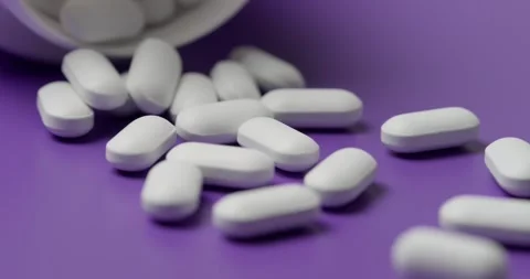 White tablets spilling out of open bottle on to surface Stock Footage 303088797