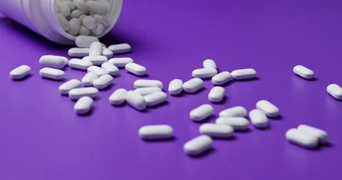 White tablets spilling out of open bottle on to surface Vidéo 303088866