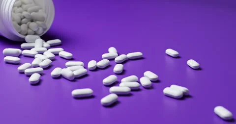 White tablets spilling out of open bottle on to surface Vídeos de archivo 303088937