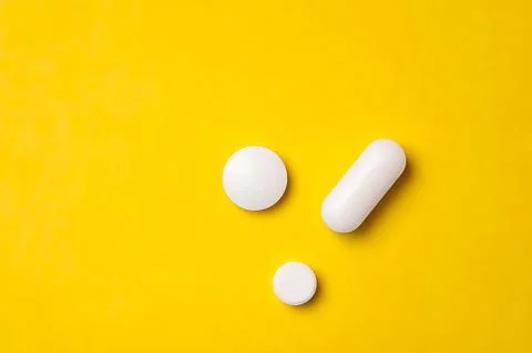 White tablets on yellow background. Different size and shape Stock Photos