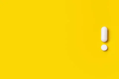 White tablets on yellow background. exclamation mark Stock Photos