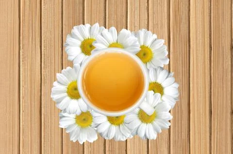 White tea cup on chamomile flowers on wooden texture close-up background Fotos Stock