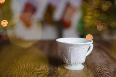 White tea cup with embossed engraving on wooden table with Christmas backgr.. Stock Photos