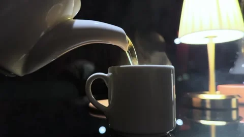 A white tea kettle is pouring water into a white coffee cup Stock Footage 286409645