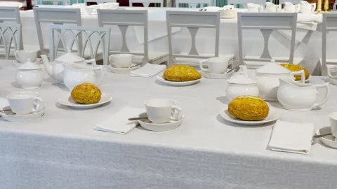 White tea sets and fresh bread cover a set dining table Stock Footage 344974275